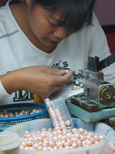 珍珠工艺师傅先在首饰空托的金针(与首饰连成一体的)上均匀地涂抹专业