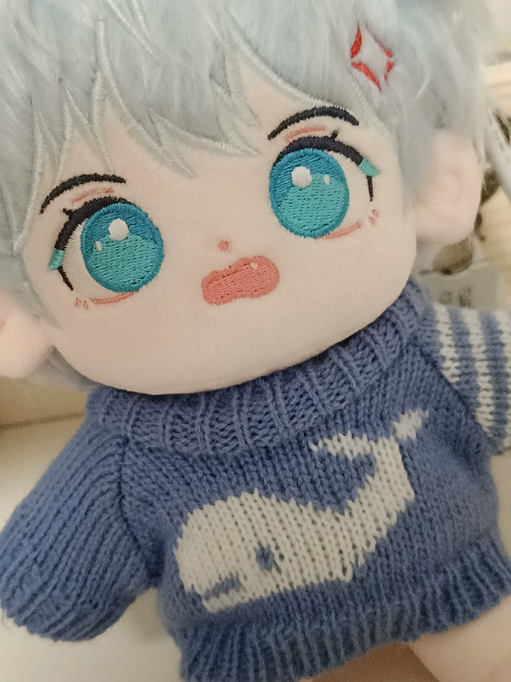 Close view of I Can Do It cotton doll embroidered eyes and knitted sweater