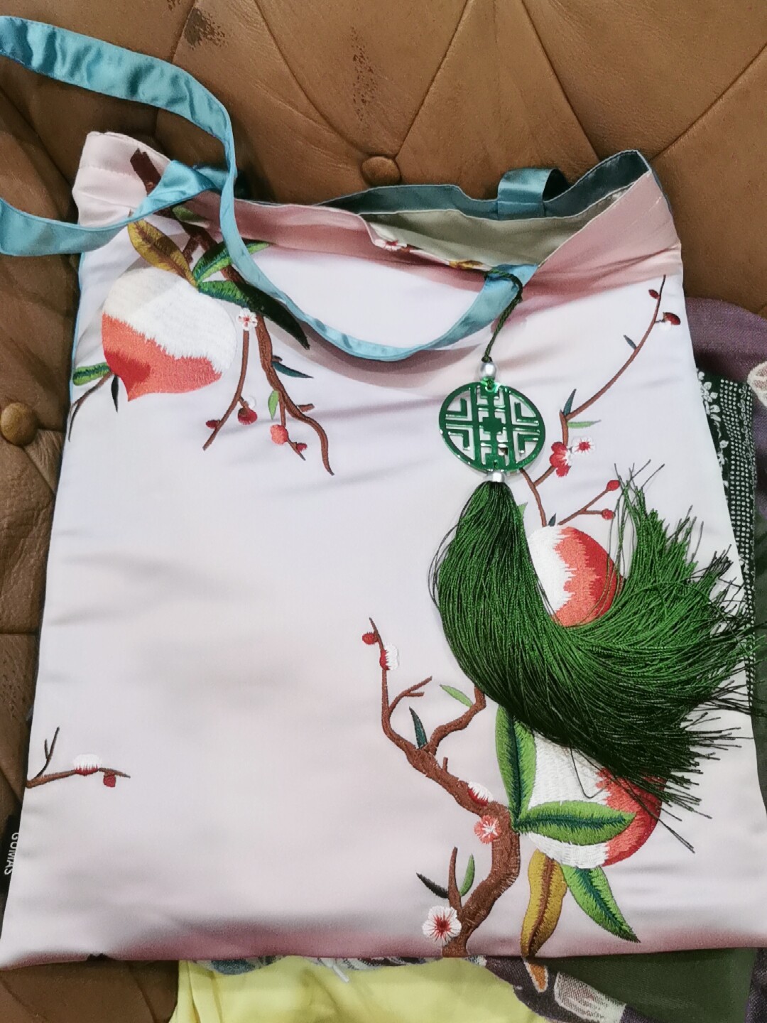 Lime green silk embroidered decorative pouch with red and white floral design and olive tassel